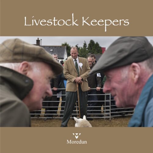 Front cover of the Livestock Keepers book. Two farmers talk at an auction, with a sheep in a pen in the background.